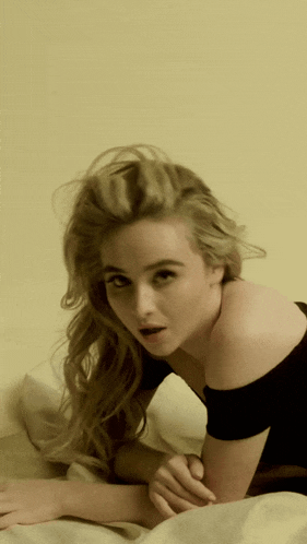 a woman with blonde hair is laying on a bed