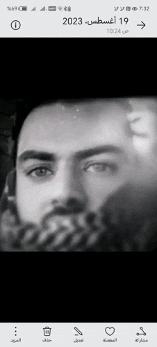 a black and white photo of a man with a beard on a cell phone .