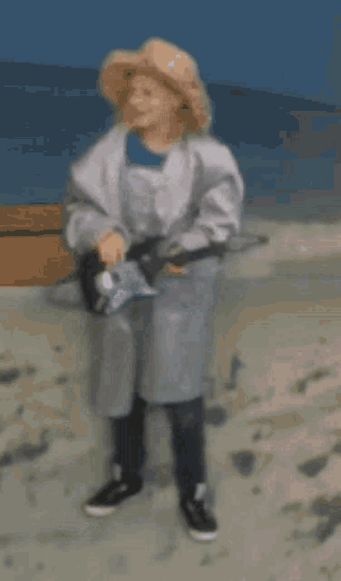 a woman in a white coat and hat is walking on a beach