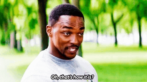 a man with a beard is talking to another man in a park while wearing a white shirt .