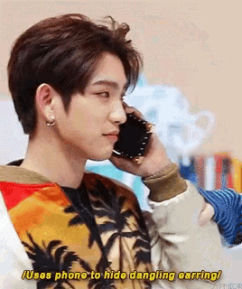 a man is talking on a cell phone while wearing a sweater with palm trees on it .