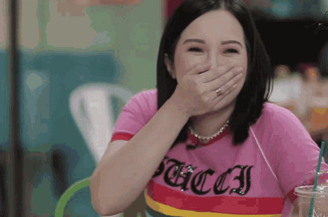 a woman wearing a pink gucci shirt laughs