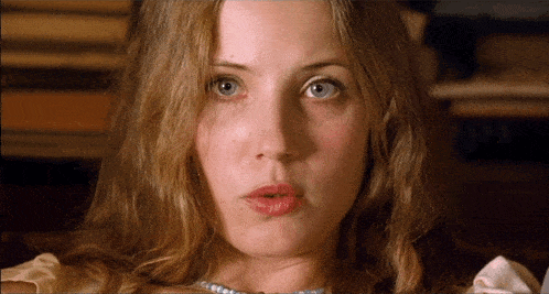 a close up of a woman 's face with a pearl necklace on