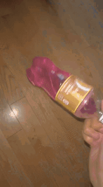 a person is holding a pink bottle with a yellow top
