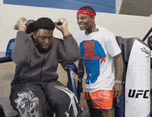 two men are standing next to a machine that says ufc on the side