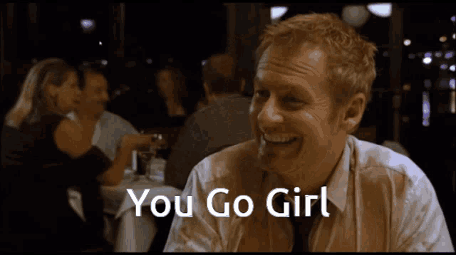 a man sitting at a table with the words " you go girl " above him