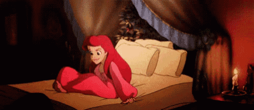 ariel from the little mermaid is laying on a bed with a candle .