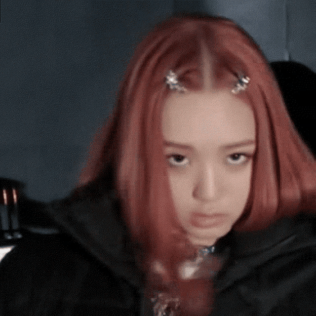 a woman with red hair is wearing a black jacket and a choker .