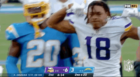 a football player wearing a number 18 jersey stands next to another player