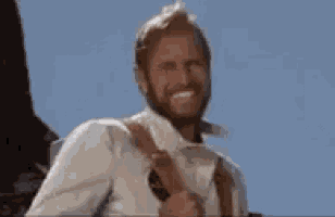 a man with a beard is smiling while holding a guitar strap .