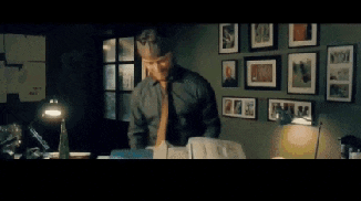 a man in a suit and tie is standing in front of a wall of pictures