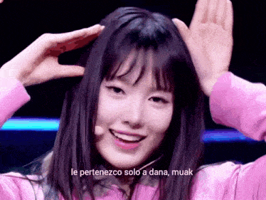 a girl in a pink shirt is making a funny face with the words le pertenezco solo a dana muak written below her