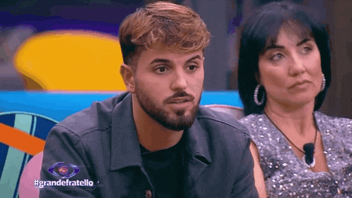 a man with a beard and a woman are sitting next to each other in a room .