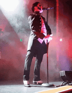 a man in a tuxedo singing into a microphone on a stage