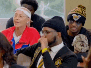 a group of people are sitting in a classroom wearing beanies .