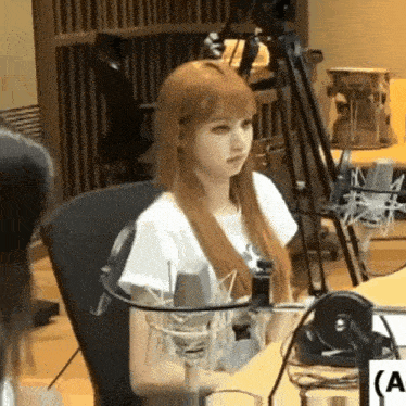 a woman with long red hair is sitting in front of a microphone in a studio .