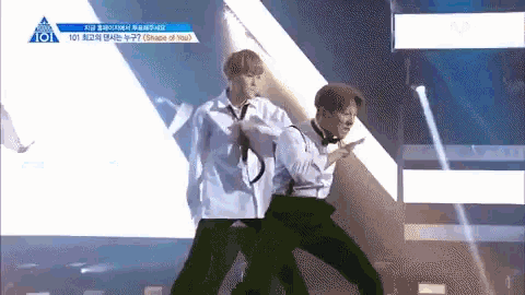 a couple of men are dancing on a stage in front of a crowd .