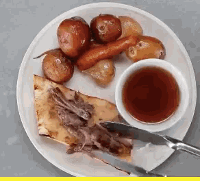 a white plate topped with meat potatoes and a bowl of syrup