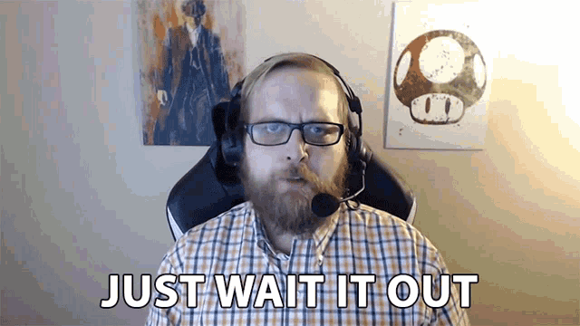 a man with a beard wearing headphones and glasses says " just wait it out "