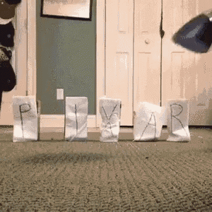 a person is throwing a frisbee in a room with the word pixar written on paper bags .