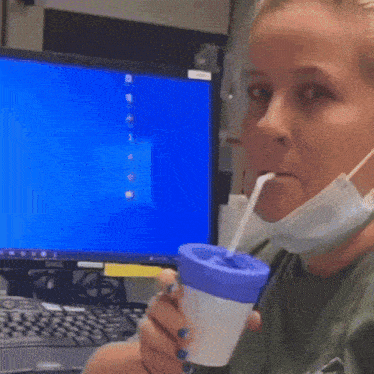 a woman wearing a mask and holding a cup with a straw