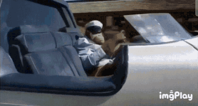 a man in a white hat is driving a car with the word imgplay on the bottom