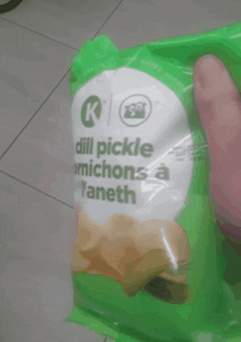 someone is holding a bag of dill pickle cornichons a l' aneth