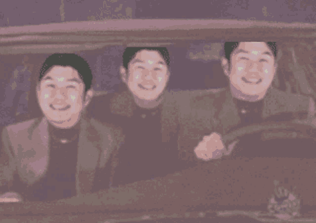 three men are sitting in a car smiling and looking out the window