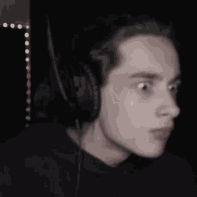a man wearing headphones holds his hand to his mouth in a black and white photo