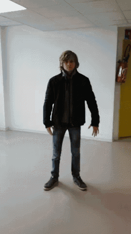 a man wearing a black jacket and jeans stands in a hallway