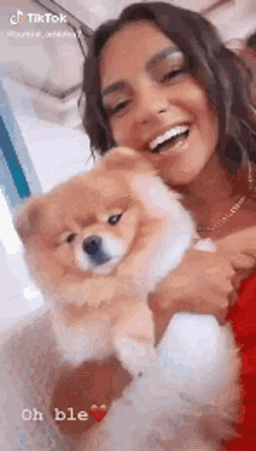 a woman is holding a small brown dog in her arms .