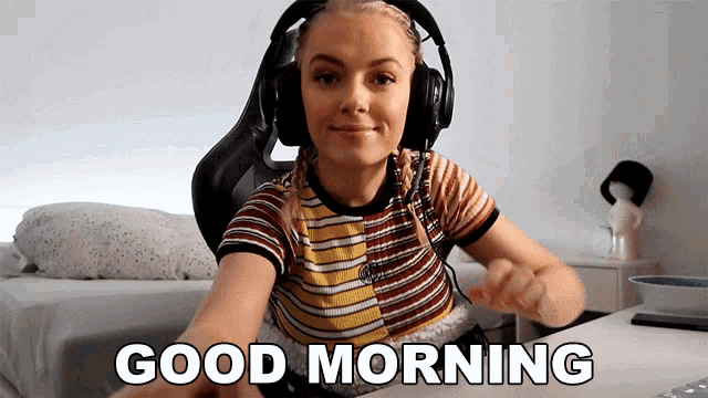 a woman wearing headphones says " good morning " while sitting at a desk