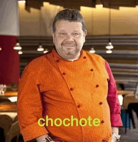 a man in a chef 's uniform is standing in a restaurant .