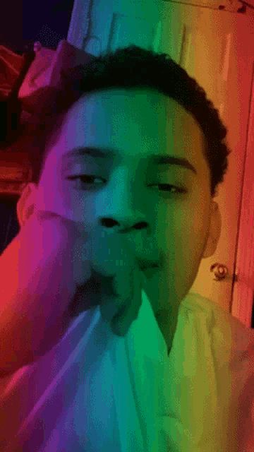 a young man covering his mouth with his hand in front of a rainbow door