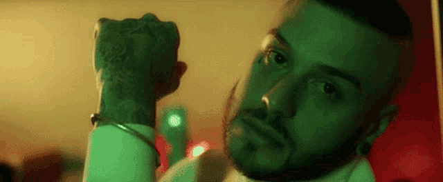 a man with a beard is holding his fist up in the air in a green room .