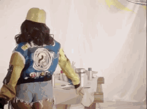 a woman wearing a blue jacket and shorts is standing in a room .