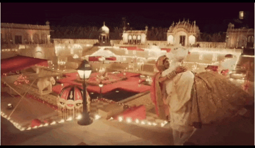 a bride and groom are kissing in front of a decorated courtyard .