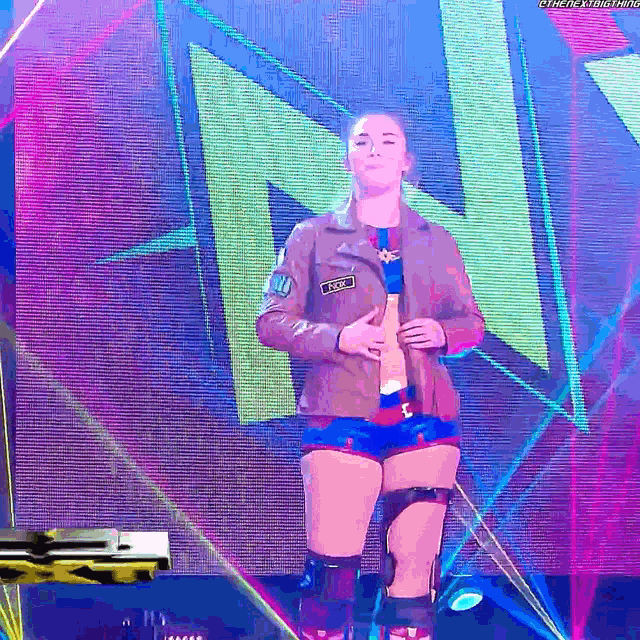 a female wrestler is standing in front of a huge n on a stage