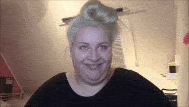 a woman with blue hair is smiling and wearing a black shirt .
