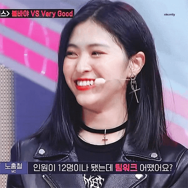 a woman wearing a choker and a leather jacket is smiling while holding a microphone .