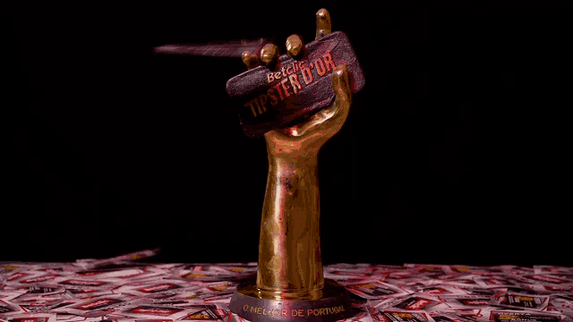 a gold trophy with a hand holding a brick that says tipster d' or
