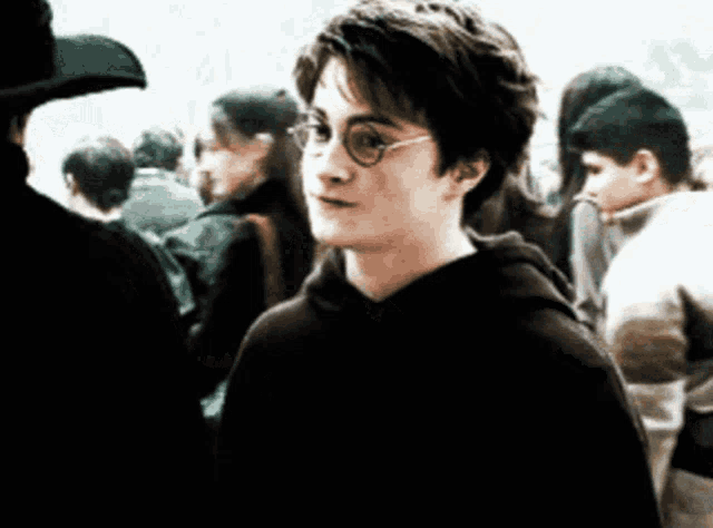 a young boy wearing glasses stands in a crowd