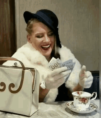 a woman is sitting at a table with a purse that has the letter j on it .