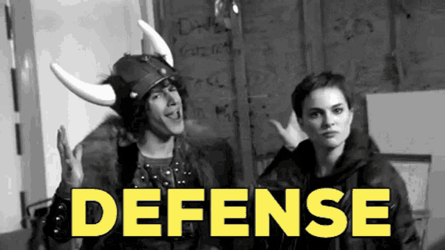 a man wearing a viking helmet stands next to a woman with the word defense in yellow