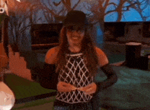 a woman is wearing a blue hat and black gloves and making a funny face .