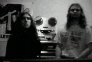 two men are standing next to each other in front of a mtv sign