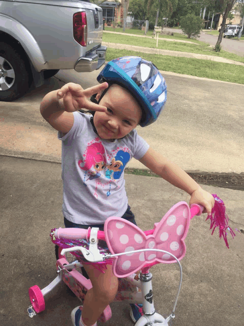 a little girl wearing a spiderman helmet rides a bike