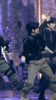 a group of young men are dancing on a stage in front of a crowd .