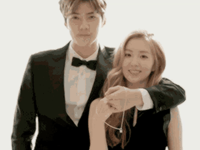 a man in a suit and bow tie holds a woman 's arm
