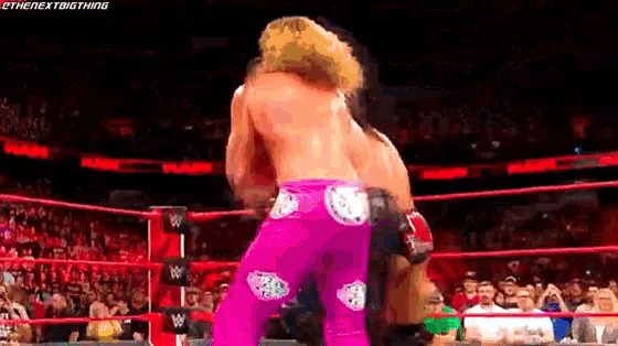 a man in pink pants is wrestling another man in a ring .